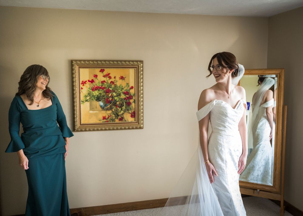 Wedding party members getting ready in a room with floral artwork on the walls.