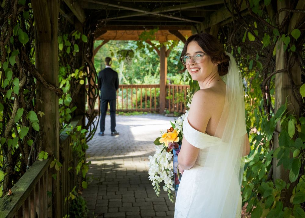 A joyful moment captured in a vine-covered garden arbor on a sunny wedding day.