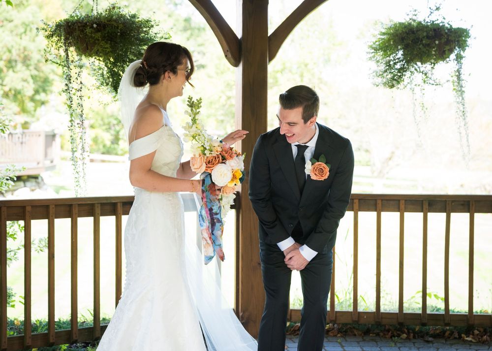 Couple sharing an intimate first dance moment under a wooden pavilion surrounded by greenery.