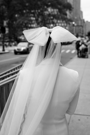 Close-up details of a flowing white wedding dress veil and train against an urban background.