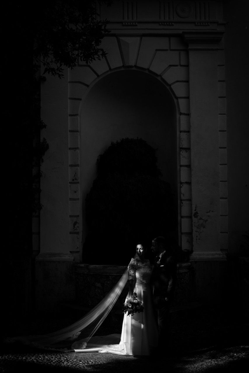 A dramatic black and white wedding photo series showing a couple silhouetted in an arched doorway with beautiful lighting.