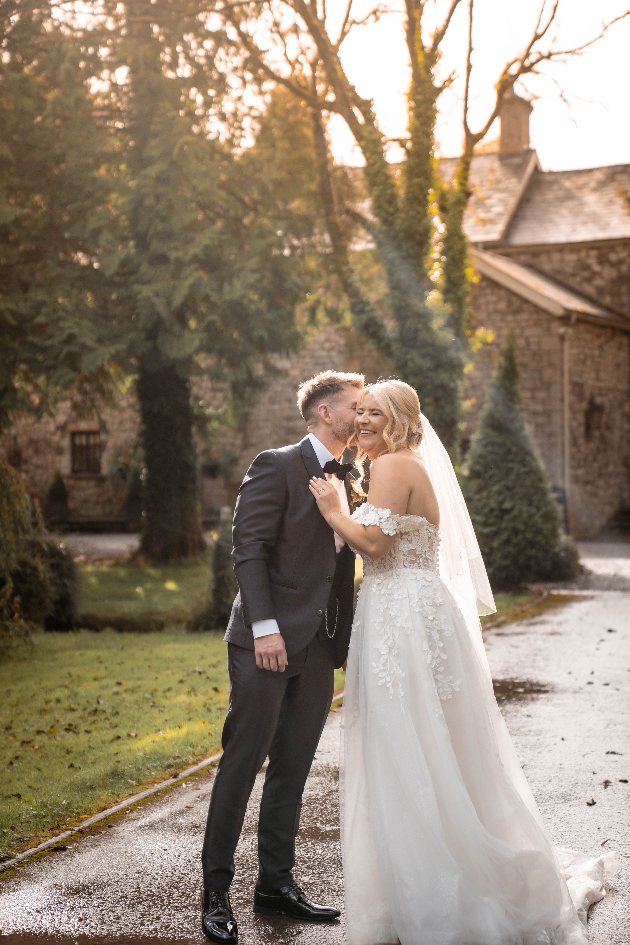 A romantic wedding couple shares an intimate moment together on a tree-lined pathway during golden hour.