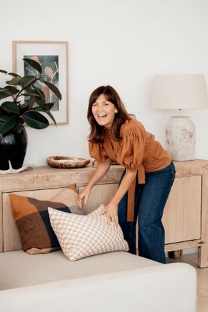 Interior scene of someone arranging decorative pillows on a modern console table.