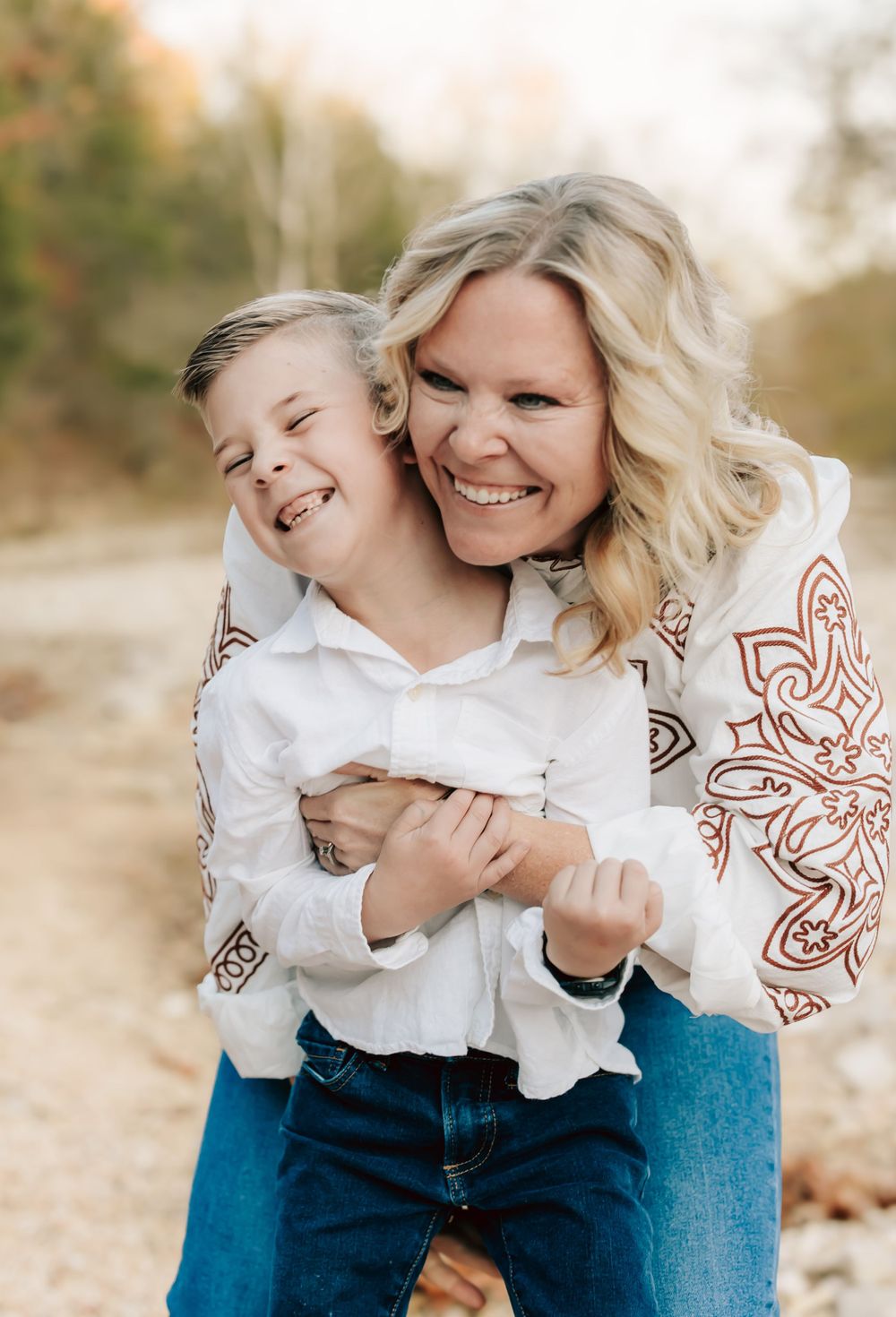 A joyful moment captured outdoors showing warm embraces and genuine laughter while wearing casual attire.