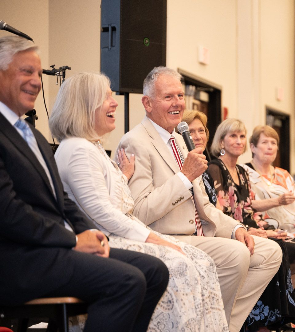 Pixs By Tina captures families sitting together receiving Edward Jones' awards, with the honoree holding mic speaking to audience.