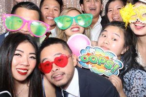 Large group of adults enjoying Flawless Photos Photo Booth with fun props at a wedding.