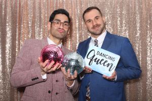Flawless Photos Photo Booth captures a male couple enjoying our open air booth with fun props at a wedding.