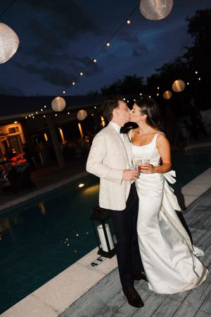 Couple dancing near a poolside at night with hanging lanterns and string lights.