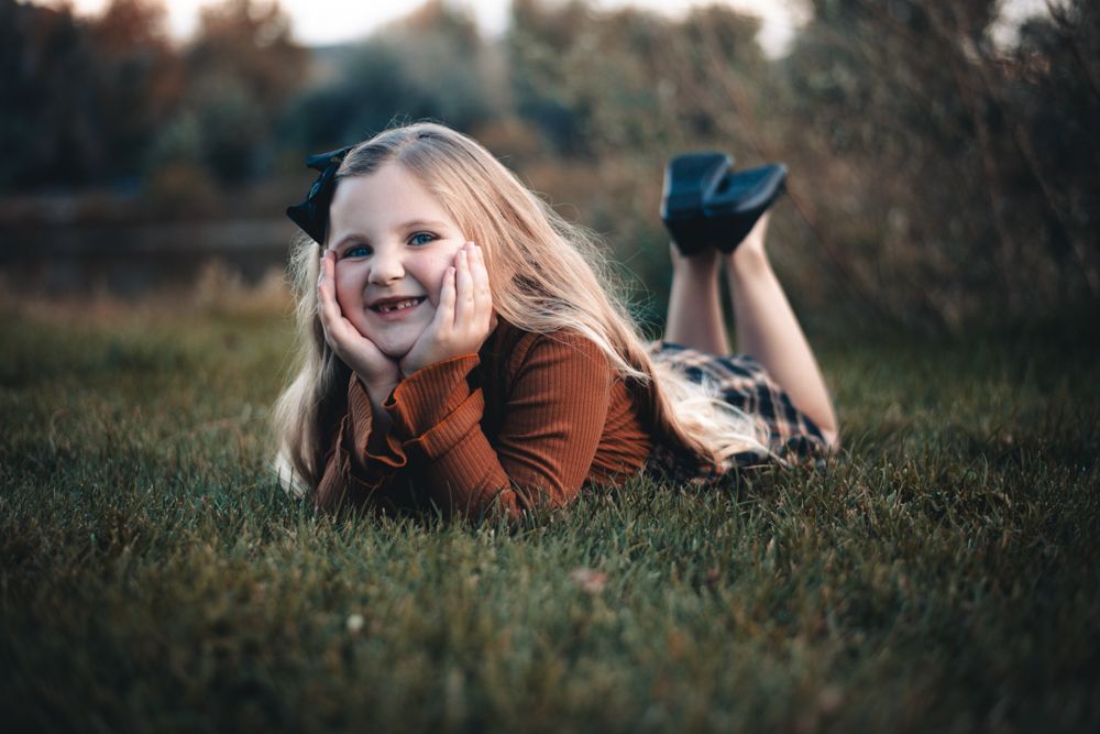 Portrait of a small child leaning on a wooden fence with a joyful expression.