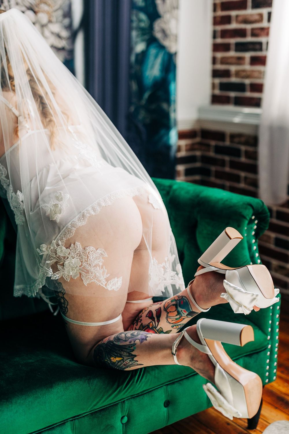 Bridal Boudoir Photography in Loganville with bride wearing a white wedding dress and veil sits on an emerald green velvet couch