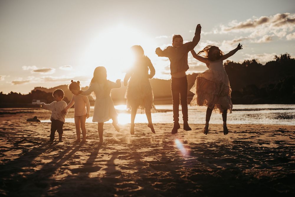 Silhouette of a joyful family jumping on a sandy beach at golden sunset.