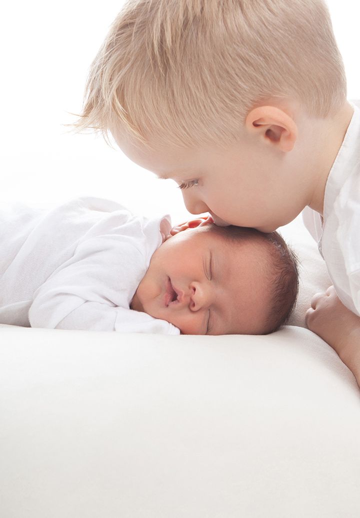 A series of gentle tender moments between a young child and baby shown in soft white tones.