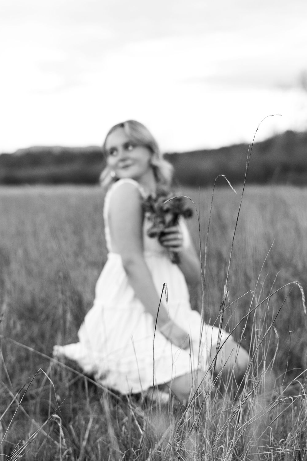 Black and white artistic portrait in a serene field of tall grass.