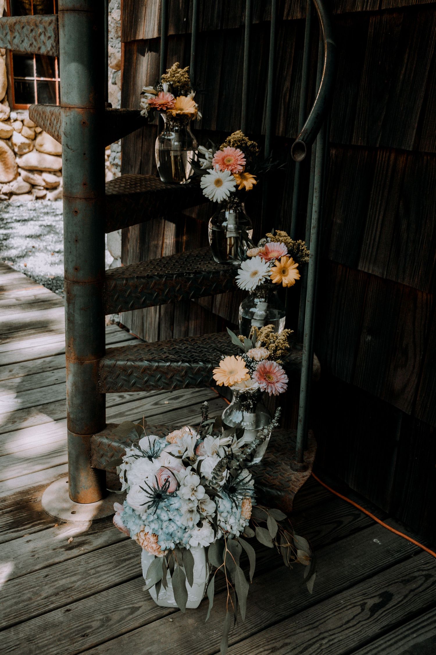 Beautiful floral arrangements with pink and white blooms cascading down rustic wooden stairs.