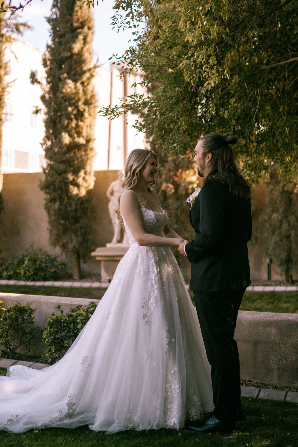Elegant wedding couple sharing a moment in a garden at sunset.
