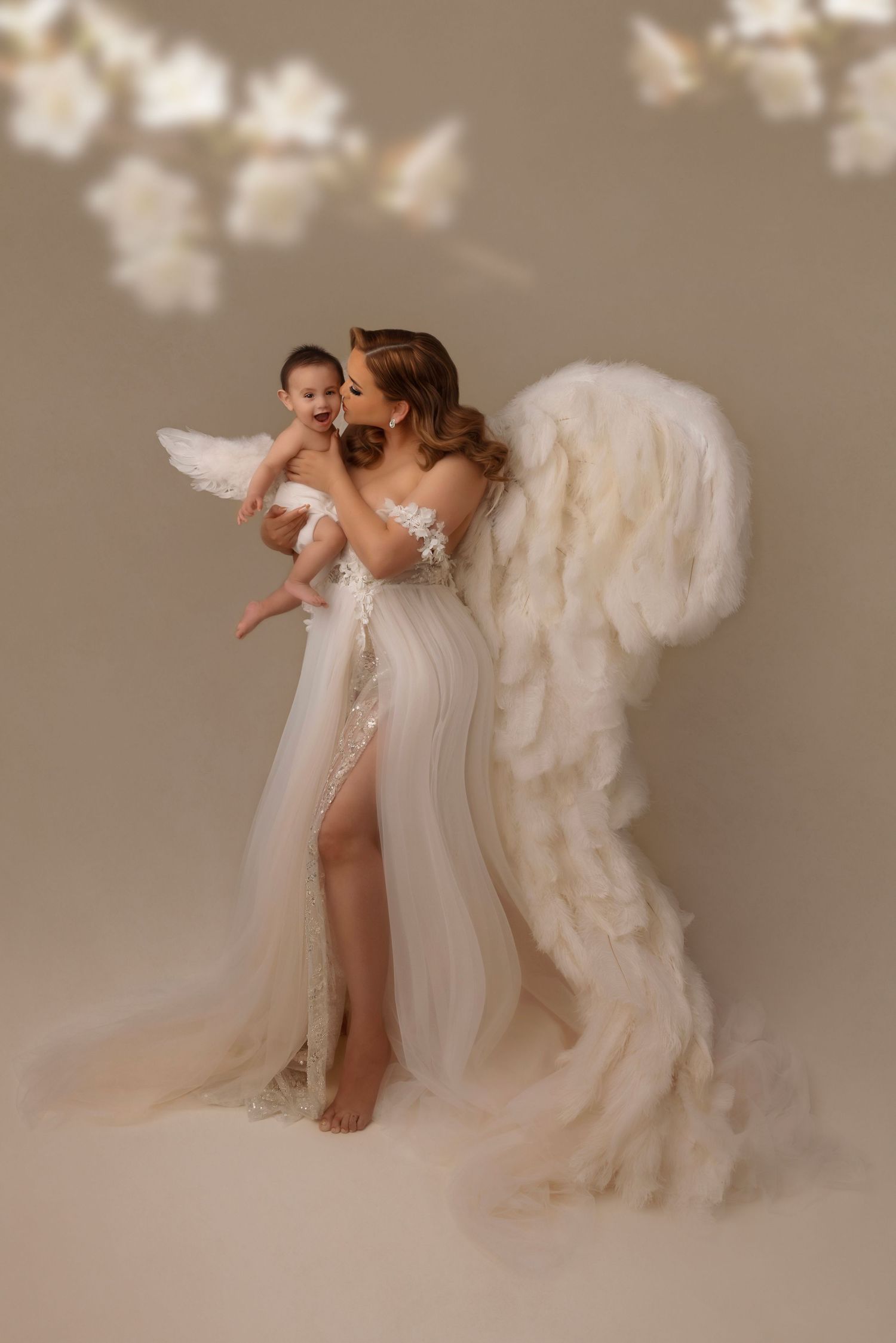 Dreamy portrait with flowing white dress and angel wings against neutral background.
