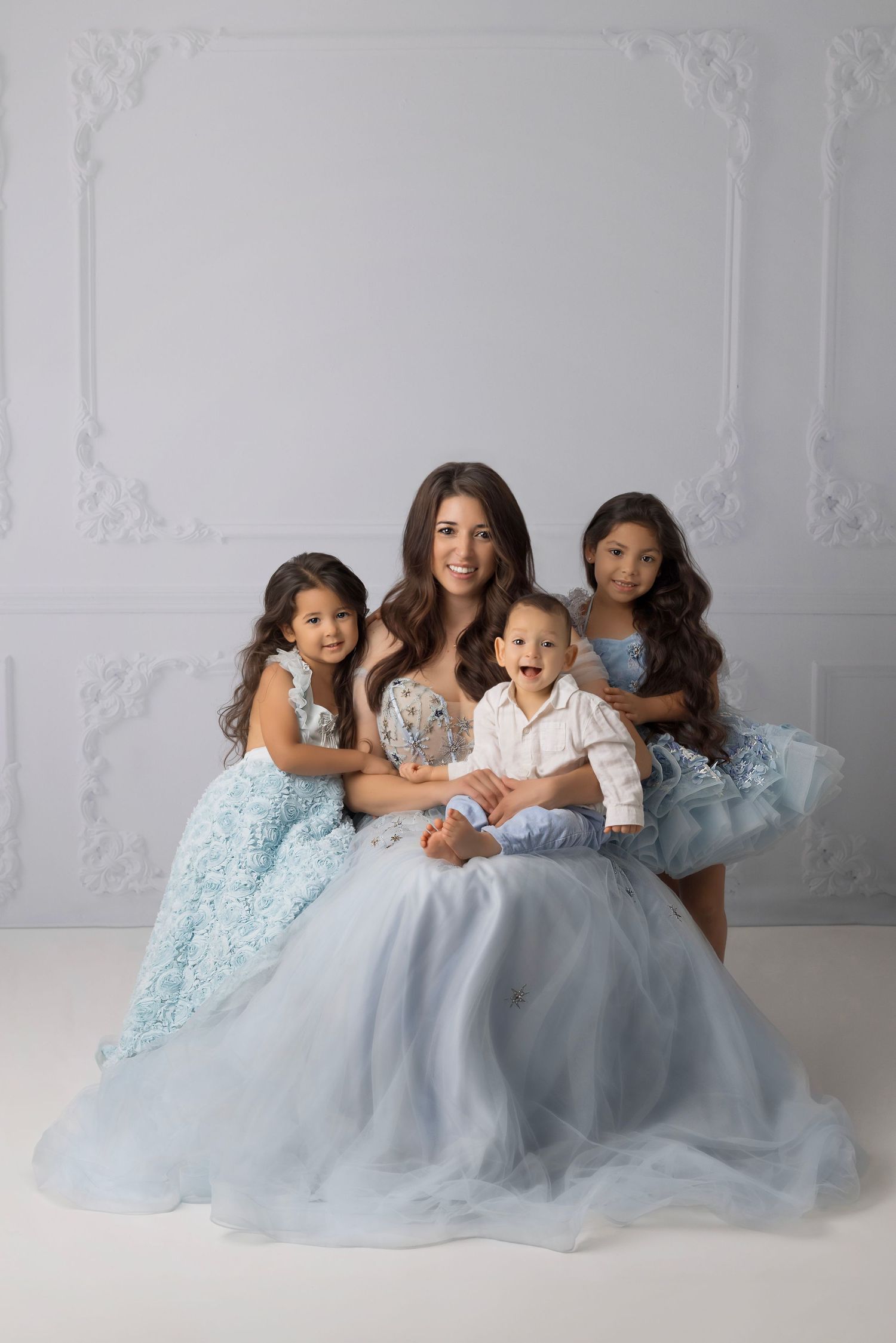 Portrait in soft blue and white tones against elegant wall paneling.