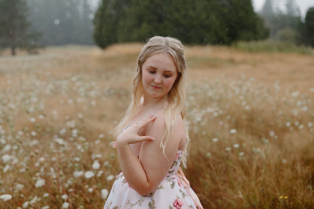 A dreamy portrait in a golden field shows a flowing floral gown with delicate details.