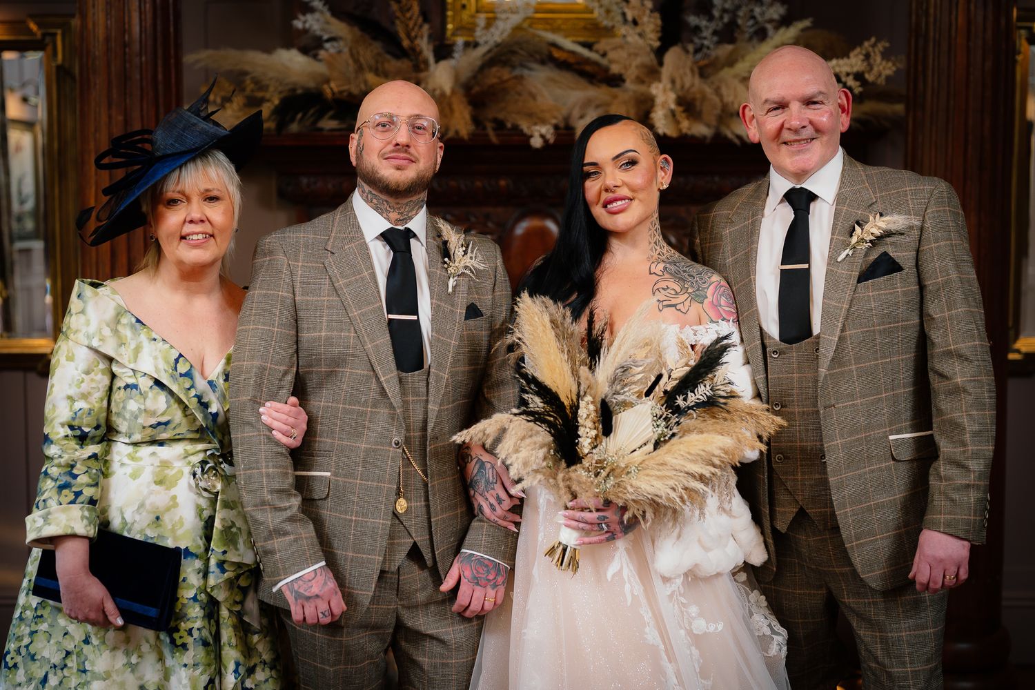 Wedding party in coordinated formal attire poses together against wooden backdrop.