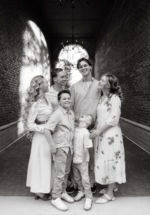 Black and white photo of children in formal white attire playing in brick tunnel.