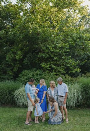 Large family group gathered in a circle playing games in a lush green garden setting.