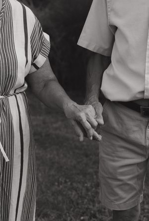 Black and white detail shot of people holding hands while wearing striped and solid clothing.