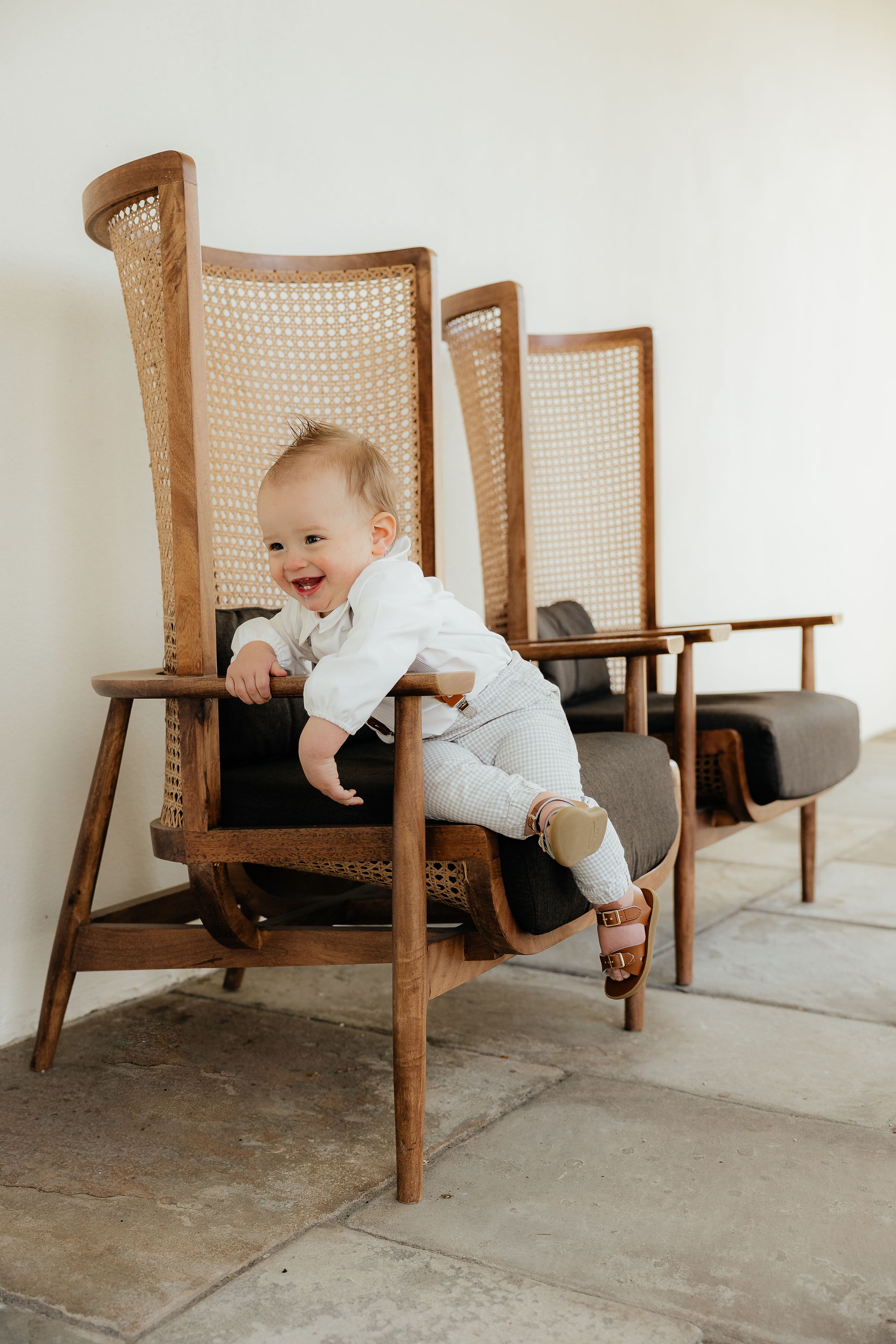 Sequence showing a baby in white crawling around vintage wooden chairs.