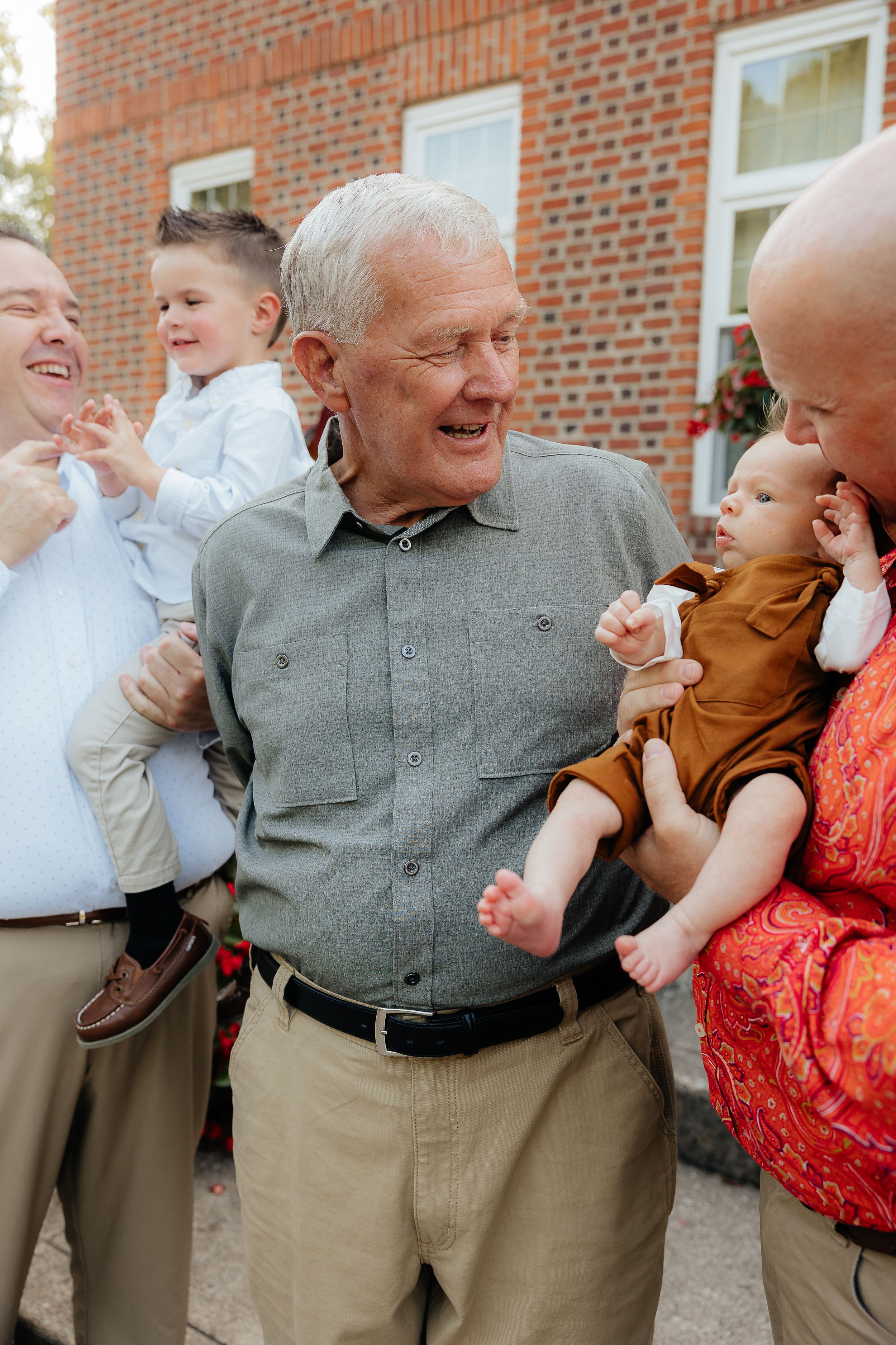 Candid laughing moments between generations during outdoor family photo session.