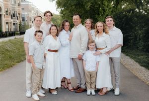 Family group in coordinated white and neutral outfits poses outdoors for portraits.