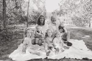 Family sitting together on a white blanket for outdoor portrait session.