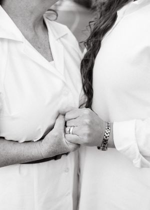 Close-up details of white formal attire and wedding rings.