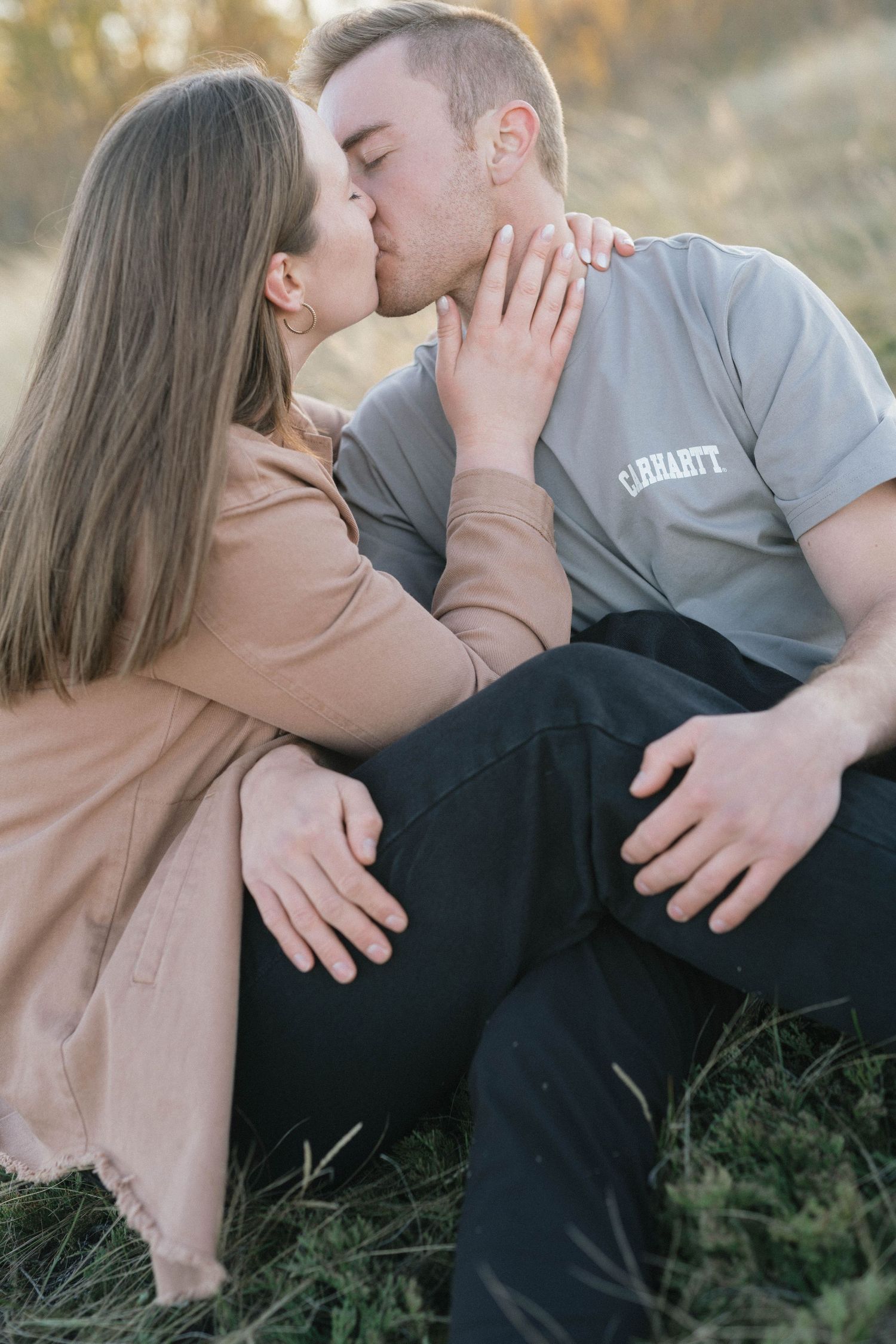 Intimate portrait of couple sharing a kiss in warm sunset lighting.