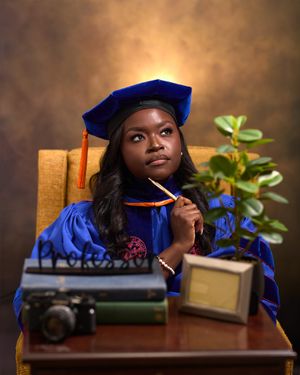 Academic portrait with vintage props including camera and books on wooden desk.
