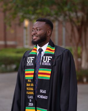Graduate wearing black academic regalia with colorful kente stole celebrating commencement at University of Florida.