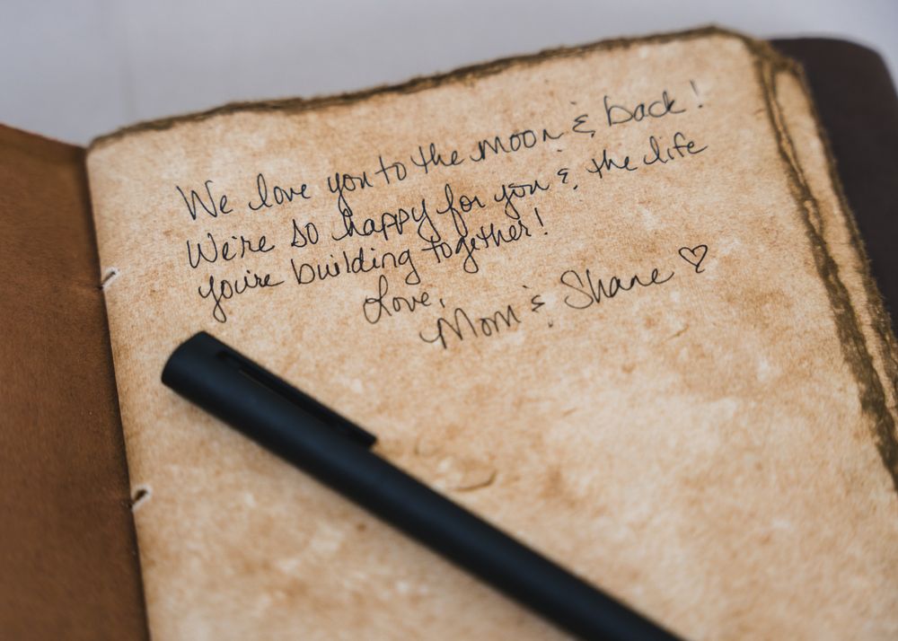 Handwritten note in vintage journal reading love message from Mom and Shane with a black pen resting on aged paper.
