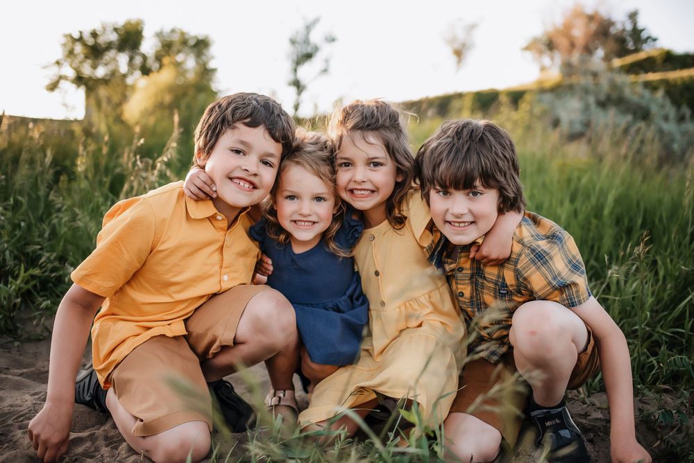 Group of four kids snuggled together during a lifestyle session in Dickinson, North Dakota - golden hour photographer serving southwest ND