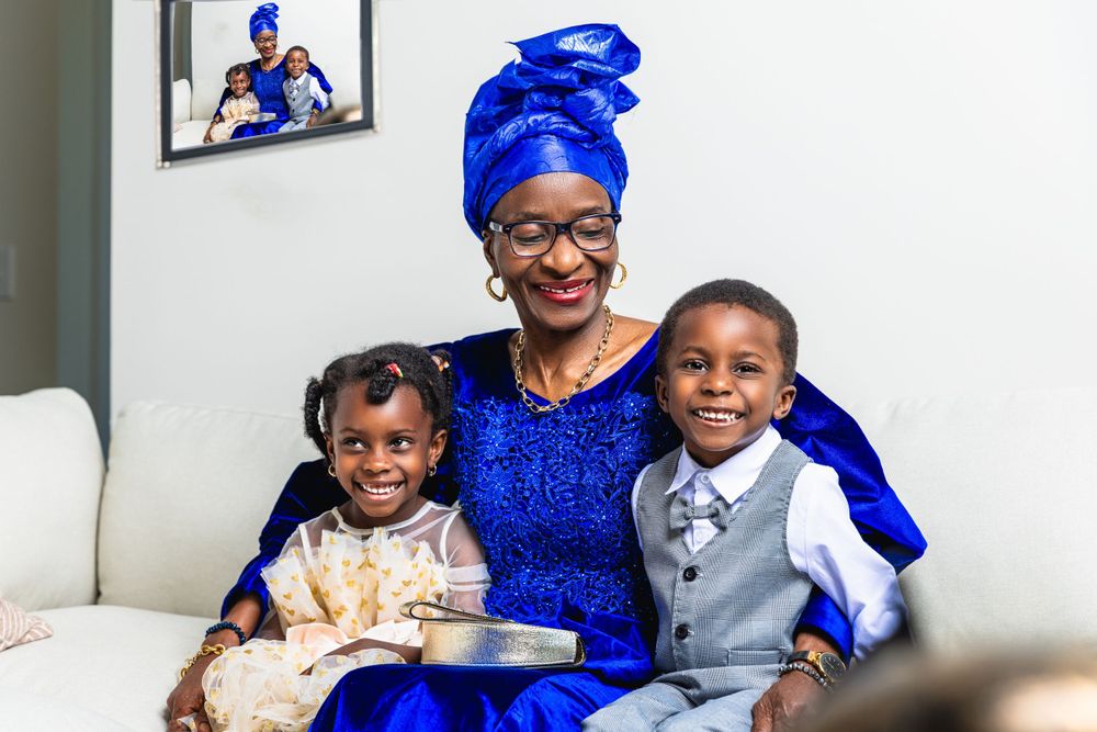 Family portrait showing woman in royal blue traditional dress with two children on white couch.