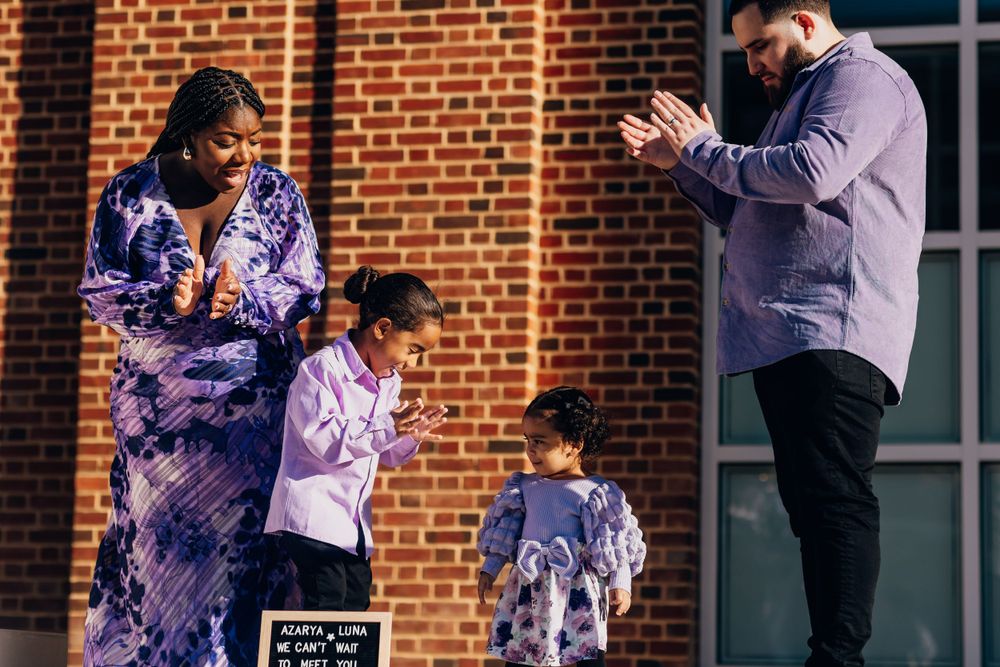 A family shares a playful moment together in front of a brick building.