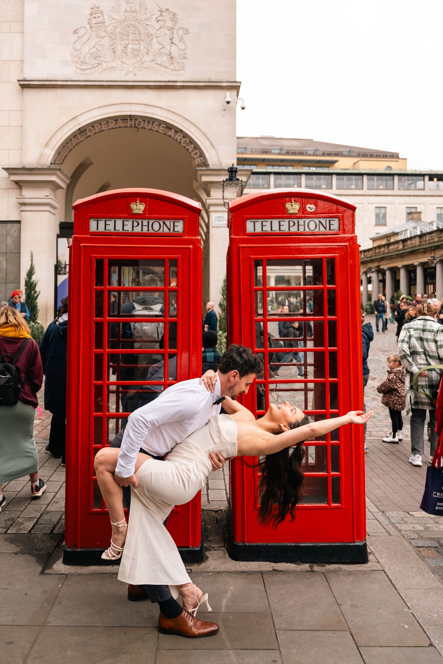 Romantic dance dip pose in front of iconic red British phone booths.