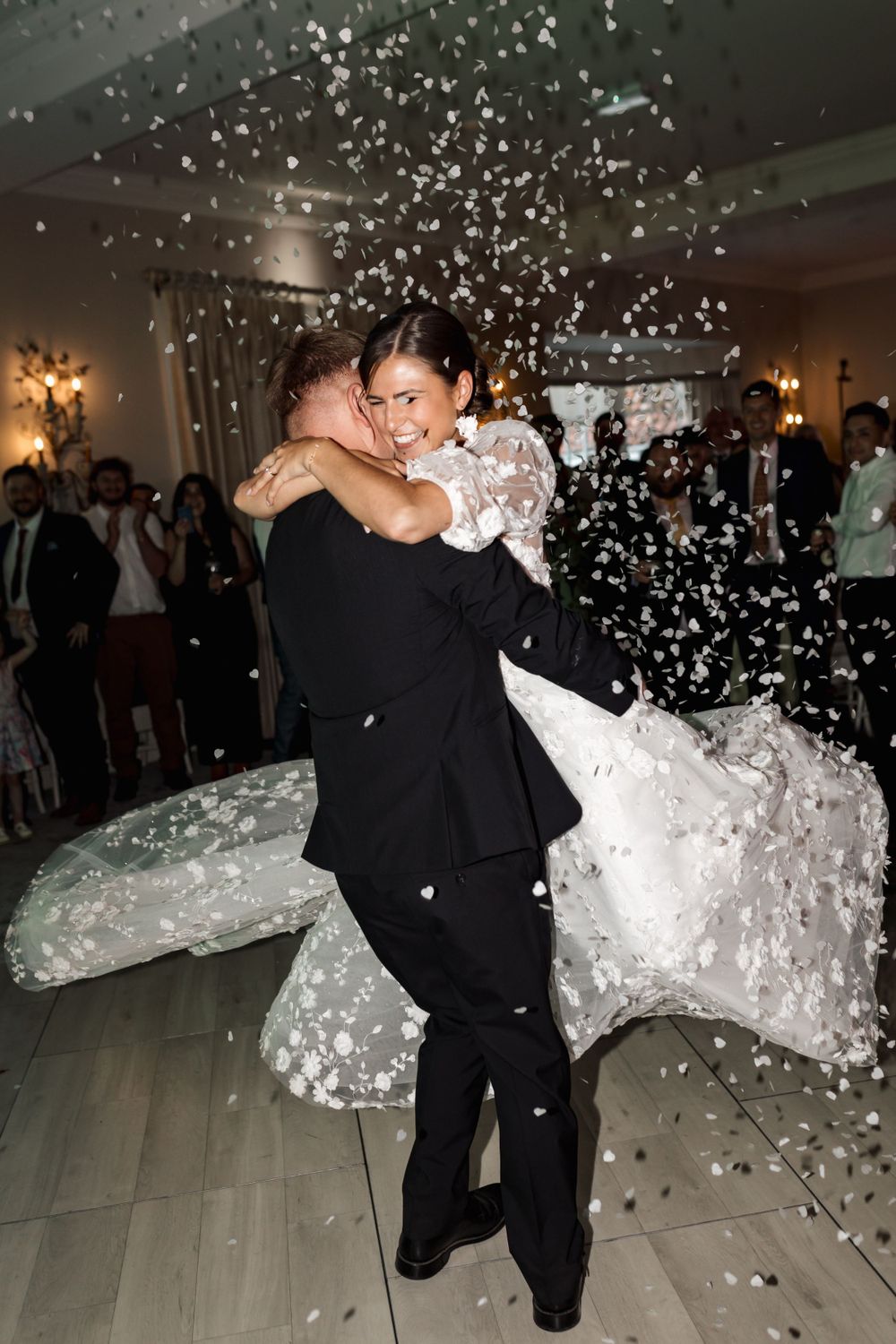 A joyful wedding dance moment captured with falling confetti and twirling dress.
