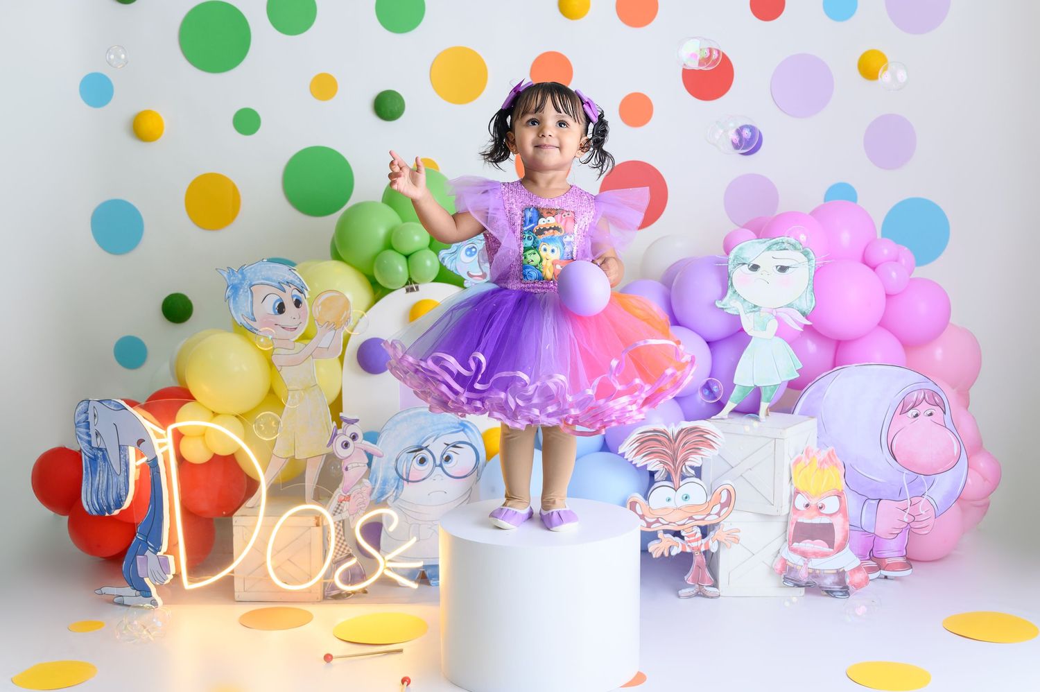 Colorful birthday setup with pastel balloons, toys, and playful decorations against white background.