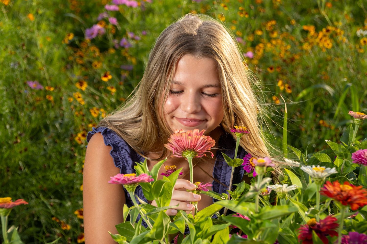 young girl in blue smelling a flower. Salem and Gloucester County family Portraits