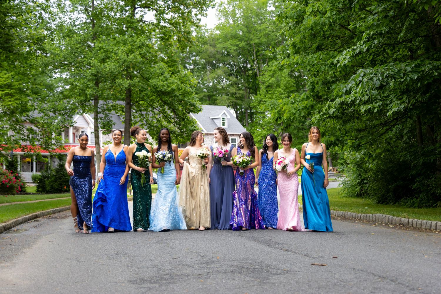 portrait of a group of girls in their prom dresses walking down a street