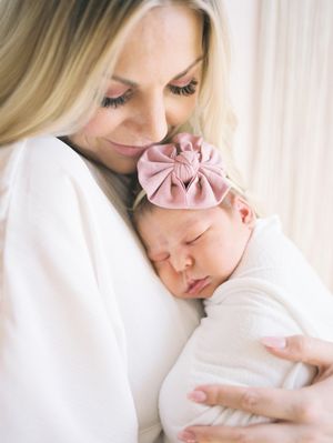 Tender moments captured in soft light as mother and newborn share intimate bonding time wrapped in white linens.