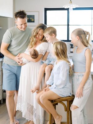 Light and airy kitchen scene with family gathering around wooden stool in casual summer clothing.