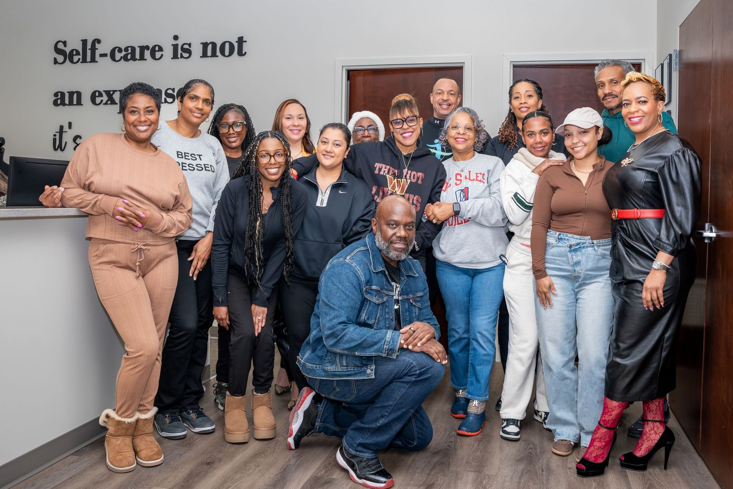 Group photo of diverse team members gathered in front of wall with inspirational text.