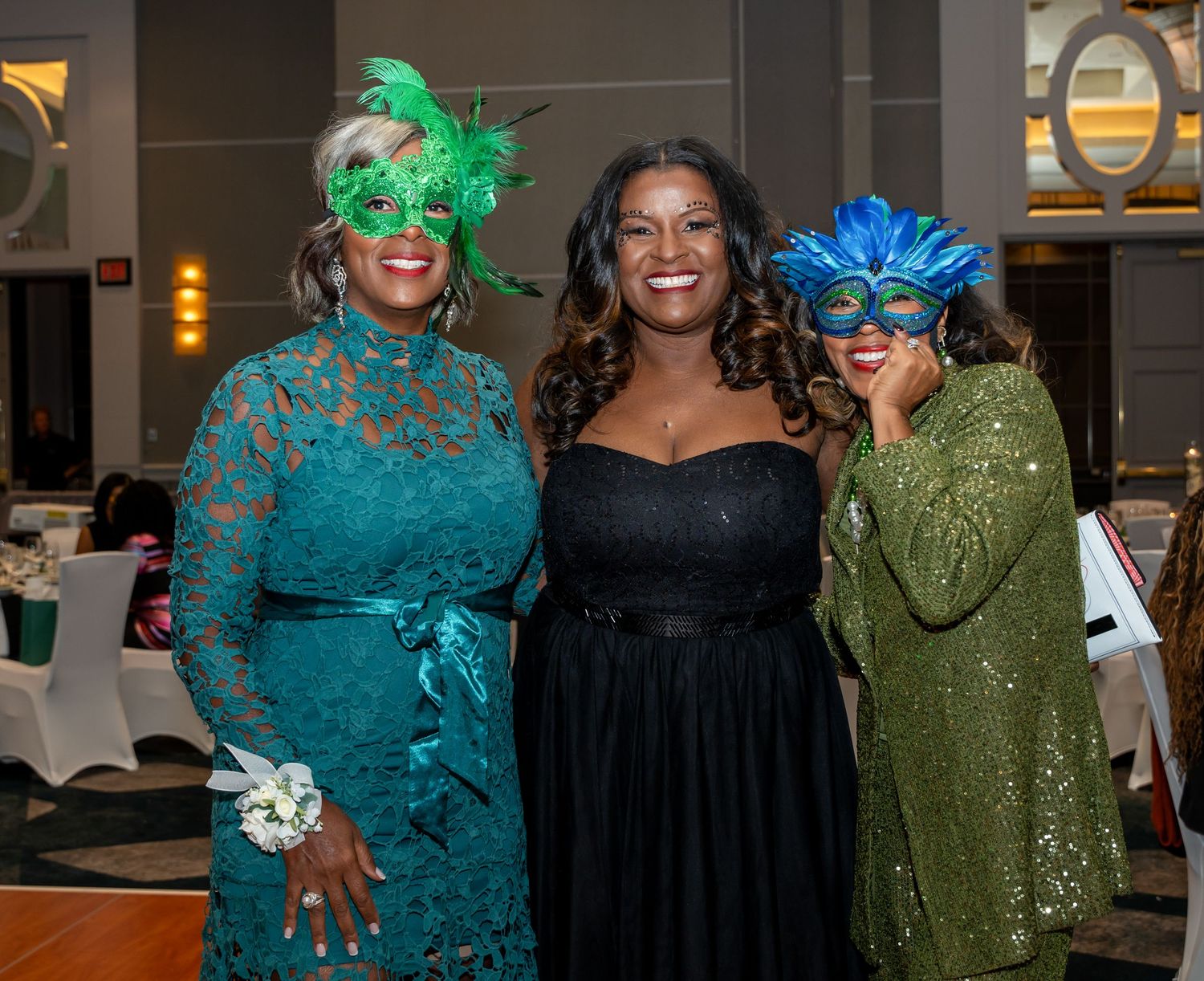 Small group photo with attendees wearing sparkly formal dresses in teal and olive colors.