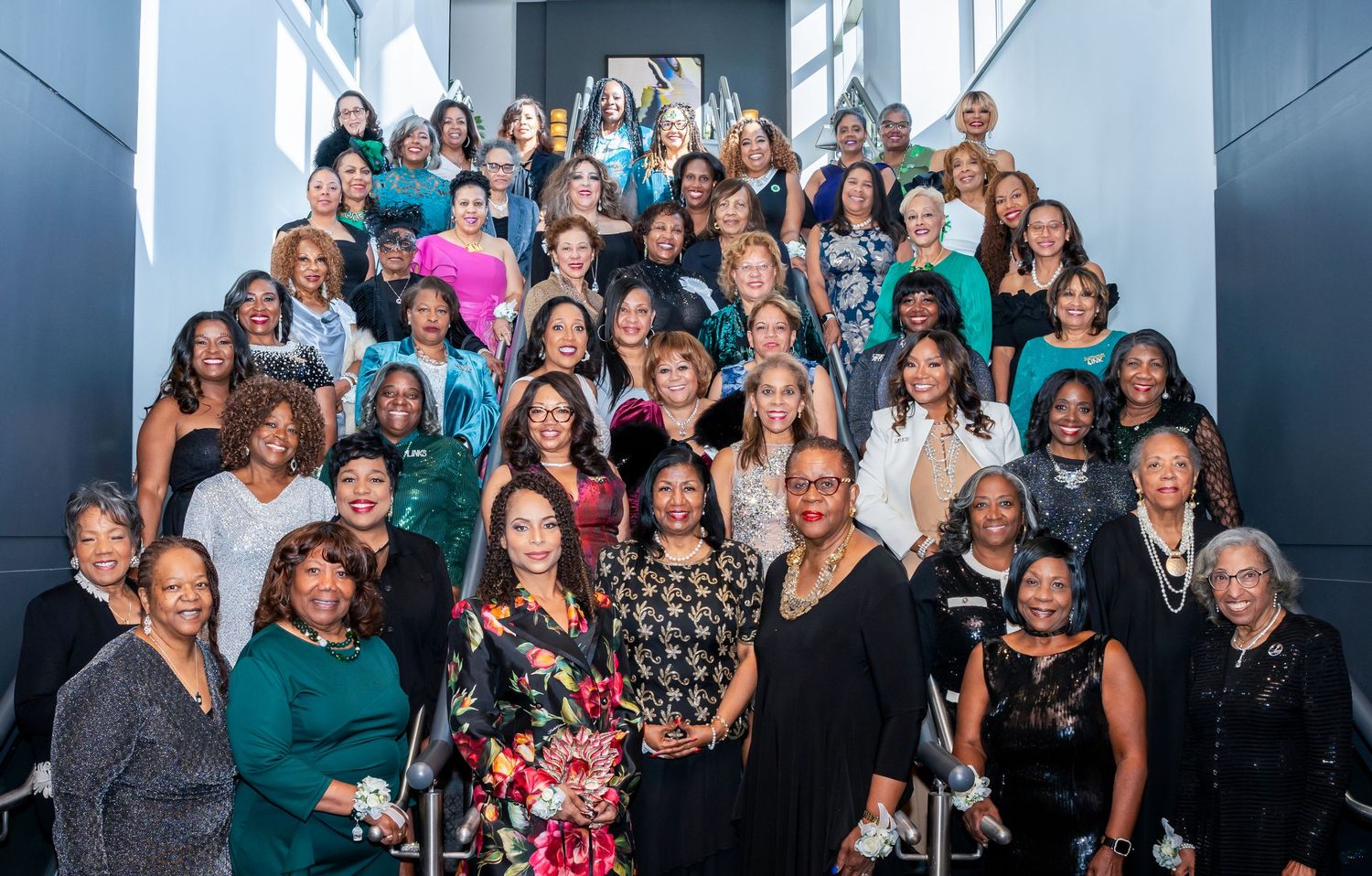 Large group of attendees smiling and posing together at an elegant formal event in a banquet hall.
