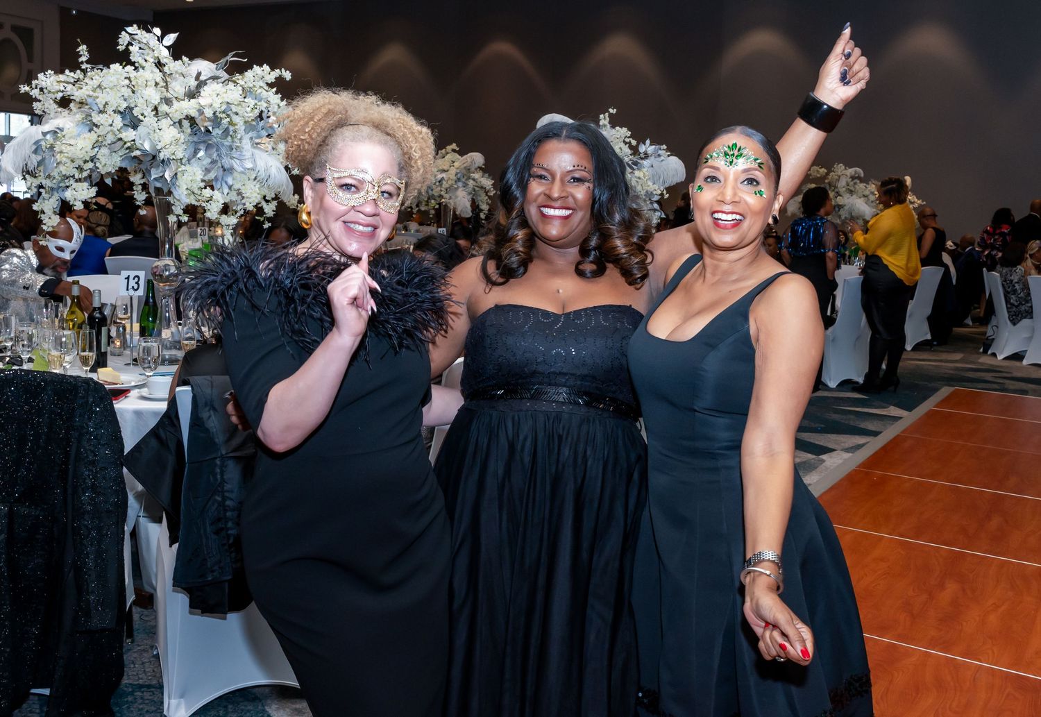 Guests in formal attire socializing and celebrating at an indoor event with decorative lighting.