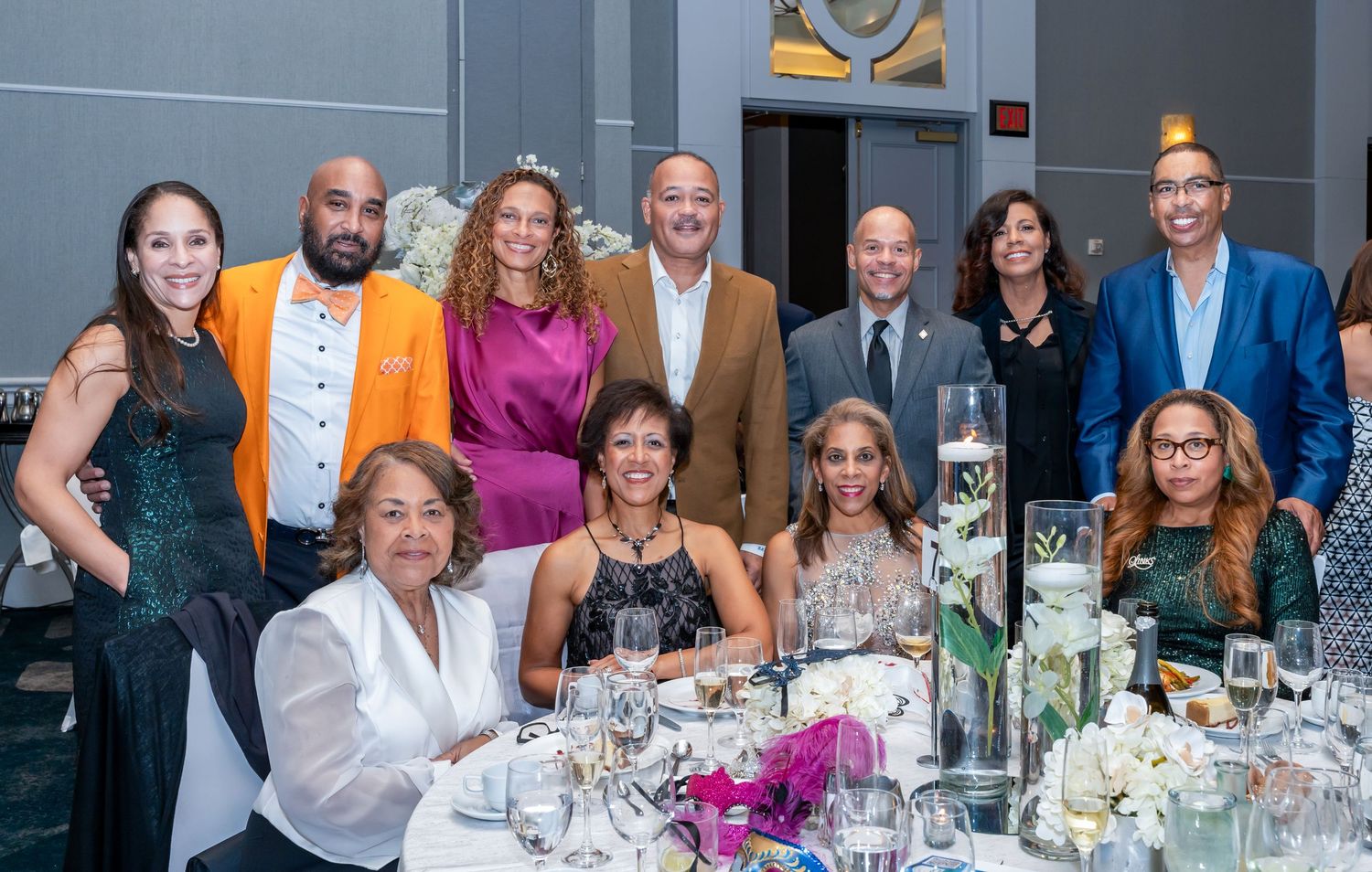 Large group of event attendees seated at decorated round tables for a formal dinner celebration.